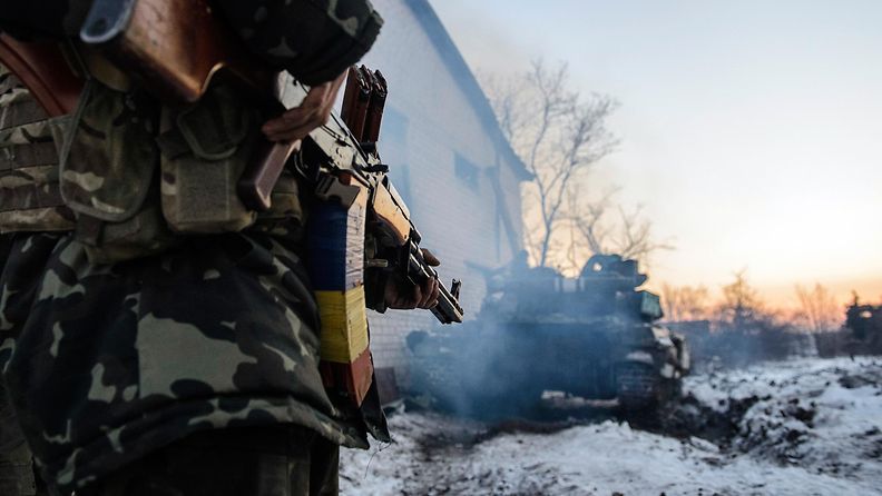 Ukrainalaissotilas tuhotun tankin edessä levottoman Donetskin alueella.