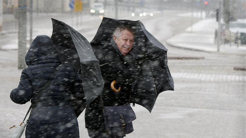 Jalankulkijat yrittivät suojautua tuulelta sekä räntä- ja lumisateilta sateenvarjoilla Helsingissä 30. maaliskuuta 2015.