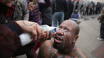 Maitoa kyynelkaasuun. Väkivaltaiset mellakat repesivät jälleen Yhdysvalloissa nuoren mustan miehen menehdyttyä poliisin käsittelyn seurauksena Baltimoressa. Kyynelkaasusta saaneen miehen silmiä huuhdeltiin kaupungissa.