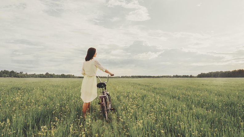 Nainen pellolla pyörän kanssa