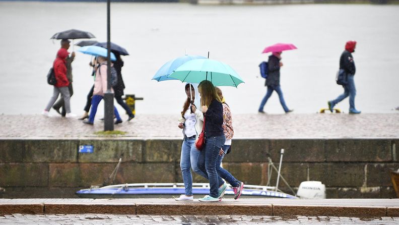 Ihmisiä sateenvarjoineen vesisateessa Kauppatorin Kolera-altaan luona Helsingissä 28. elokuuta 2015.