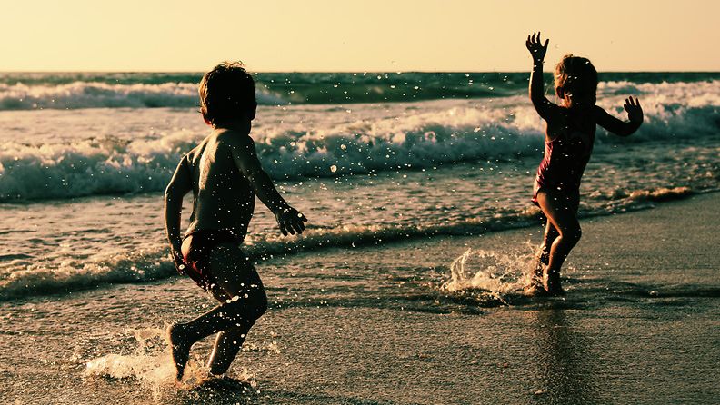 Lapset leikkivät rannalla. Tällainen kuva kelpaa myös pedofiilille. Kuvituskuva.
