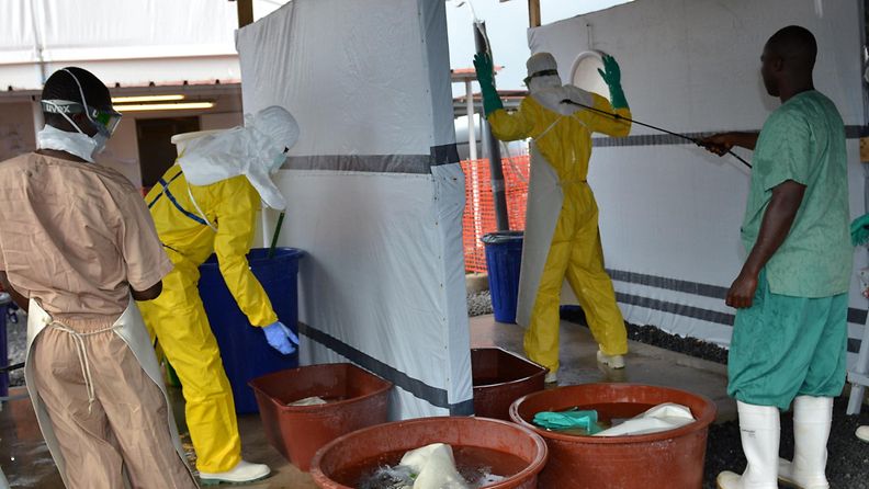 Terveystyöläiset desinfioivat ebolakeskuksen tiloja suojavarusteissa Guineassa Länsi-Afrikassa.