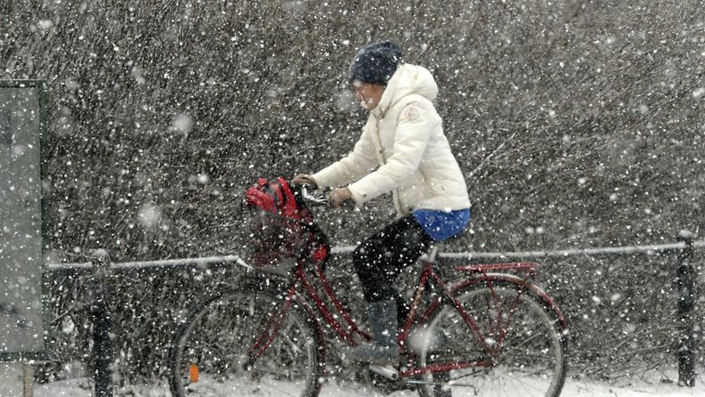 Nainen polkupyöräilee lumipyryssä Helsingissä 25. maaliskuuta 2015.