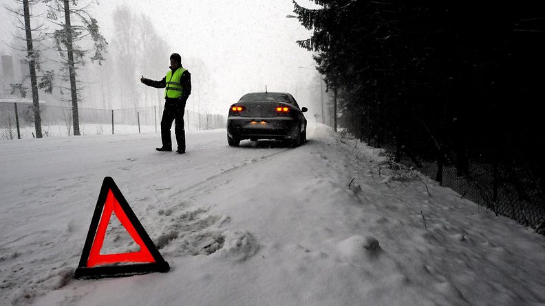 Huomioliivejä käyttävä mies kävi laittamassa varoituskolmio tielle, koska hänen autonsa jäi tienposkeen, Helsingissä 22. joulukuuta 2009. (Lavastus)