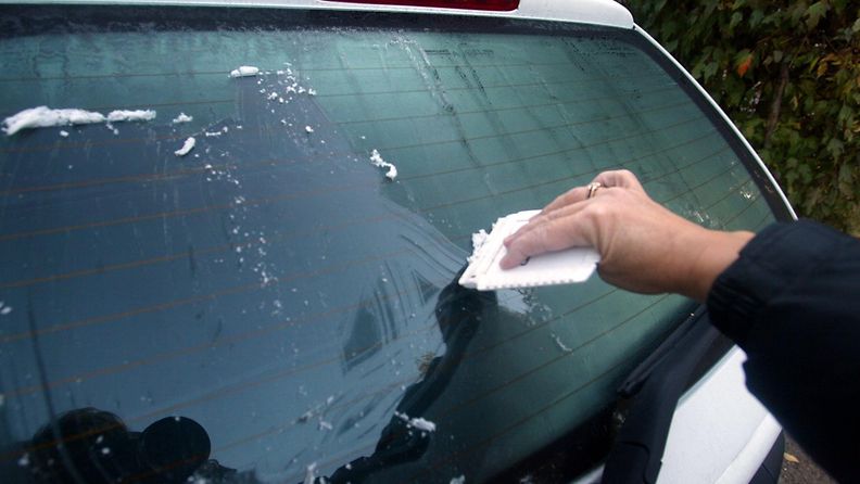 Auton ikkunaa raaputetaan puhtaaksi jäästä.