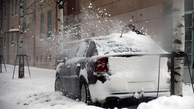 Autoa puhdistetaan lumesta Helsingissä 21. joulukuuta 2009
