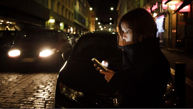 nainen käyttää puhelinta kadulla