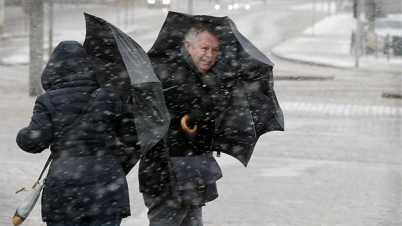 Jalankulkijat yrittivät suojautua tuulelta ja rännältä sateenvarjoilla Helsingissä 30. maaliskuuta 2015.