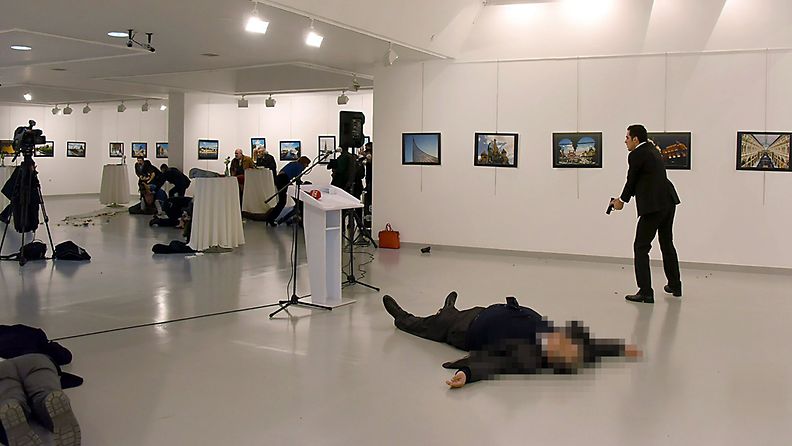 This picture taken on December 19, 2016 shows Andrey Karlov (2ndR), the Russian ambassador to Ankara, lying on the floor after being shot by a gunman (R) during an attack during a public event in Ankara. A gunman crying "Aleppo" and "revenge" shot Karlov while he was visiting an art exhibition in Ankara on December 19, witnesses and media reports said. 