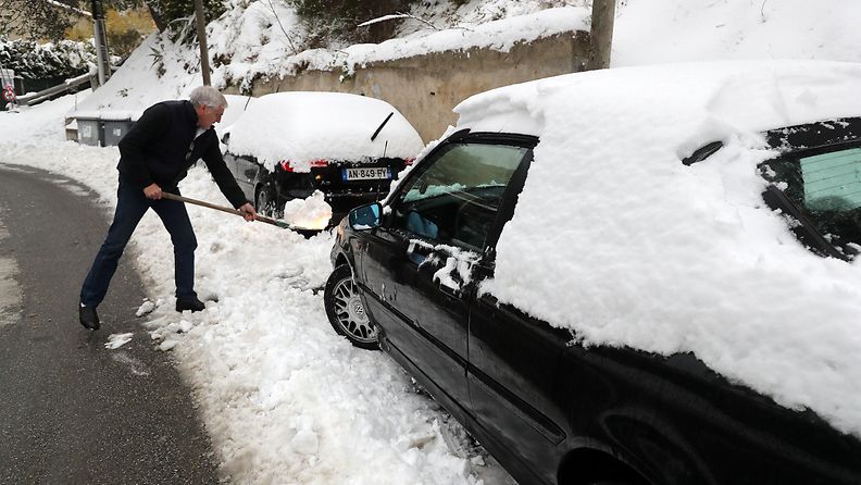 Mies kaivaa autoa lumesta Ranskassa