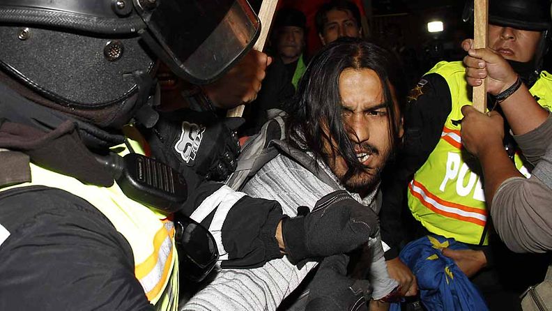 Poliisi yrittää taltuttaa mielenosottajia Ecuadorin Britannian-lähetystön edessä.