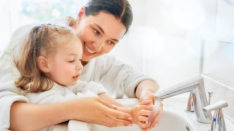 Äiti auttaa pesemään kädet