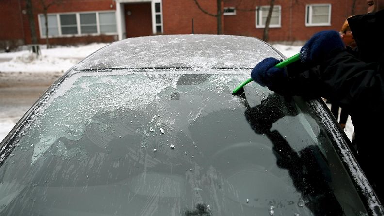 LK 23.2.2021 Mies puhdistaa auton tuulilasia jäästä Helsingissä 22. helmikuuta 2021.