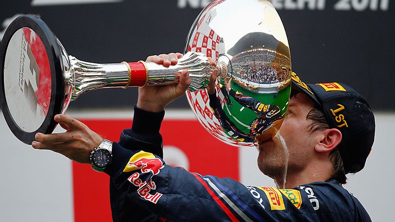 Sebastian Vettel nauttii samppanjaa Intian GP:n voittopokaalista 