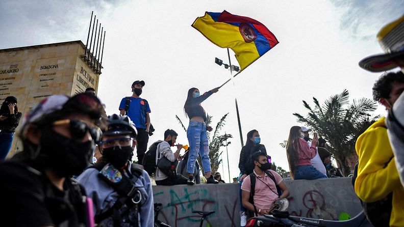Nainen heiluttaa Kolumbian lippua protesteissa presidenttiä vastaan Bogotassa.