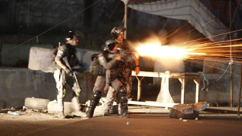 Israelin armeijan sotilaat ampuvat kyynelkaasua palestiinalaisia mielenosoittajia kohti.