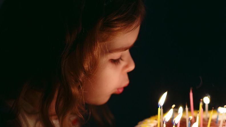 lapsi puhaltaa kynttilät