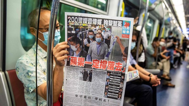 Mies lukee Apple Daily -sanomalehteä junassa Hongkongissa.