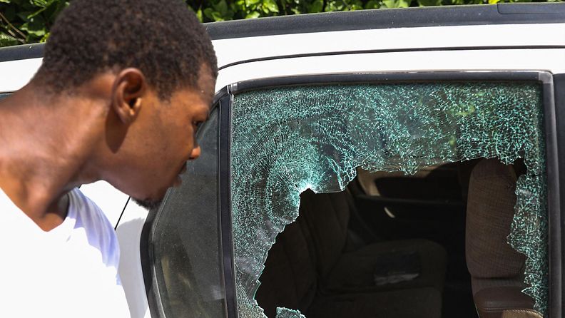 Mies katsoo luotien rikkomaa auton ikkunaa Haitissa lähellä salamurhatun presidentin asuntoa.