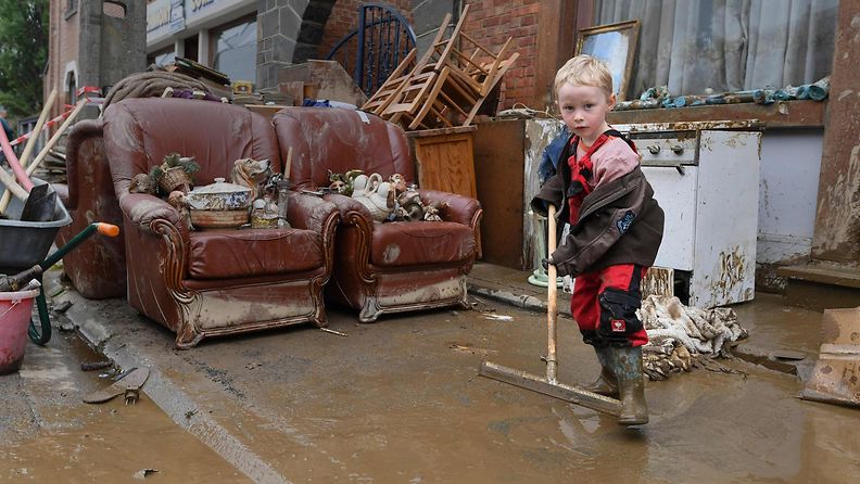 Lapsi auttaa puhdistustöissä tulvan jälkeen Saksassa.