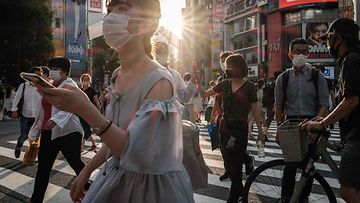 Ihmisiä kasvomaskit kasvoillaan ylittävät tietä Tokiossa, Japanissa 28. heinäkuuta.