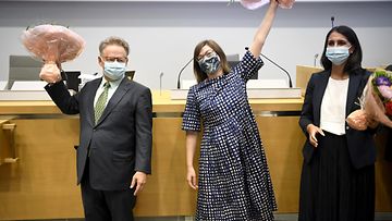 Helsingin kaupunginvaltuuston valitsemat pormestari ja apulaispormestarit tuulettavat kukkakimput käsissään ja maskit kasvoillaan.