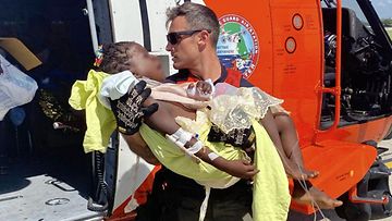 Yhdysvaltain rannikkovartija kantaa loukkaantunutta lasta pelastuskopteriin.