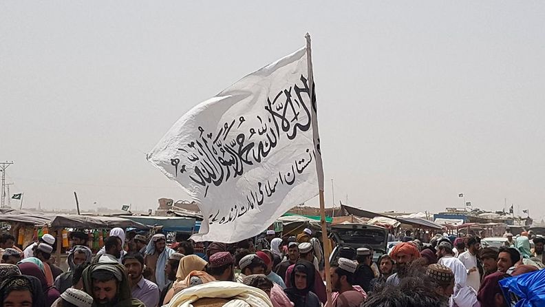 Talebanin lippu liehuu väkijoukon keskellä.