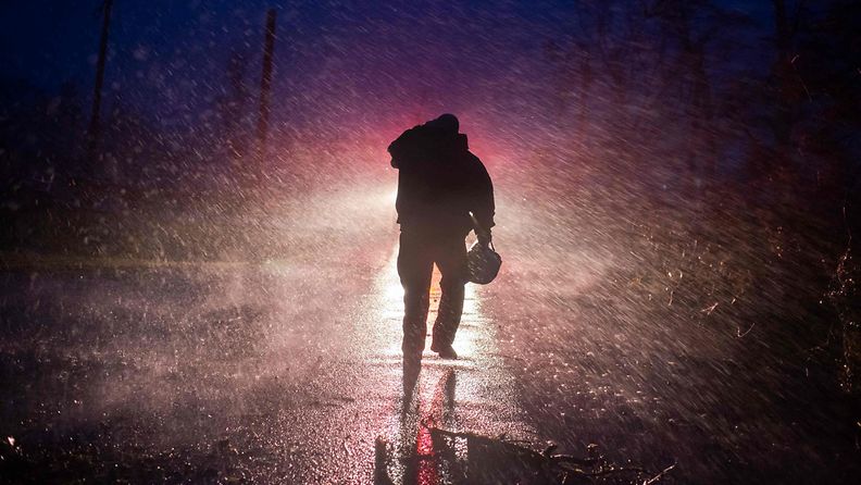 Palopäällikkö kävelee sateessa hirmumyrskyn Idan aikana.