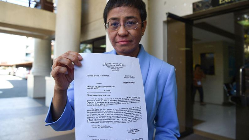 Toimittaja Maria Ressa näytti pidätysmääräystä Manilan oikeustalon ulkopuolella vuonna 2018.