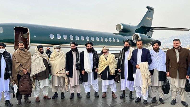 Talebanin edustajat poseeraavat suomalaisyrityksen lentokoneen edessä.