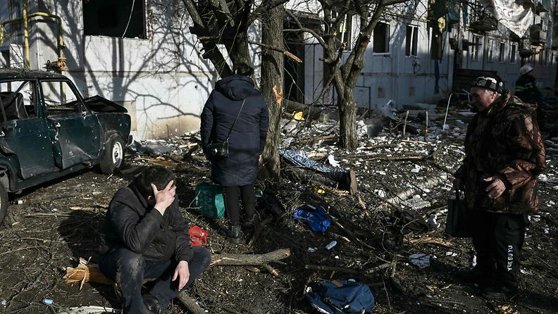 Ihmisiä pommituksessa tuhoutuneen rakennuksen ulkopuolella Tšuhujivissa, Harkovan alueella Itä-Ukrainassa 24. helmikuuta.