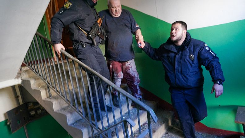 Ukrainalainen turvallisuusjoukot saattoivat loukkaantunutta miestä asuintaloon osuneen ilmaiskun jälkeen Tšuhujivissa, Harkovan alueella Itä-Ukrainassa 24. helmikuuta.