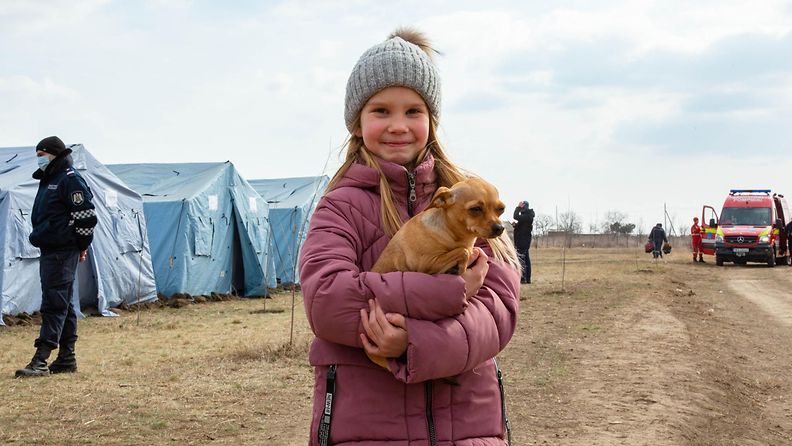 Ukrainalainen pakolaislapsi Tatiana seisoo koiransa kanssa väliaikaisen pakolaiskeskuksen edustalla Ukrainan ja Moldovan rajan lähellä.