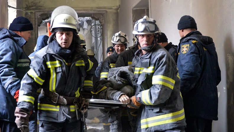 Pelastushenkilökunta kantaa loukkaantunutta ulos rakennuksesta Harkovassa, Ukrainassa.