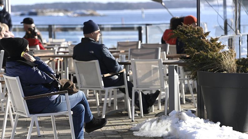 LK 11.3.2022 Ihmisiä nauttimassa auringosta kahvilassa Kaivopuiston rannassa Helsingissä maanantaina 28. helmikuuta 2022.