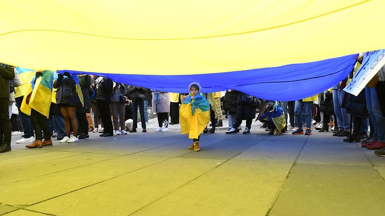 LK 12.3.2022 Lapsi käveli jättikokoisen Ukrainan lipun alla sodan vastaisessa moelenosoituksessa Pariisissa Ranskassa lauantaina 12.3.2022.