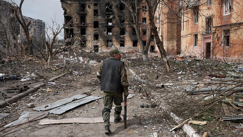 Mies kävelee raunioituneessa Mariupolissa Ukrainassa huhtikuussa 2022.