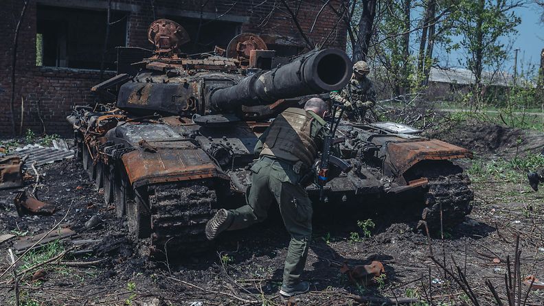 Ukrainalaisia sotilaita ja tuhoutunut venäläinen tankki toukokuussa 2022.