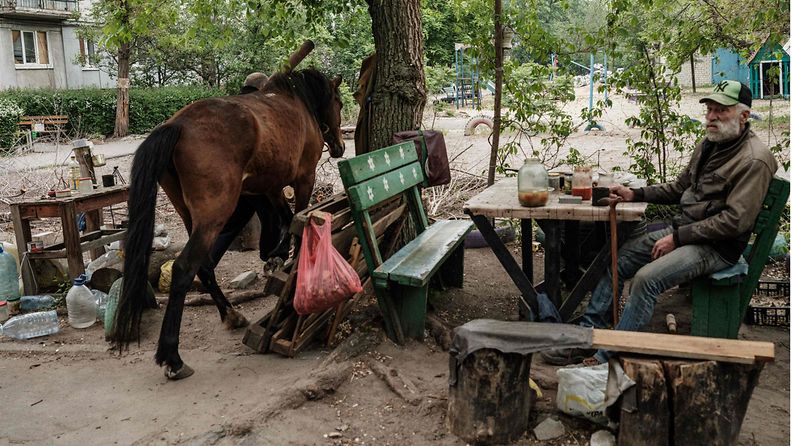 LK 29.5. Mies istui hevosensa vieressä Venäjän pommittaessa lähialuetta Sjevjerodonetskissa Itä-Ukrainassa, 18. toukokuuta 2022.
