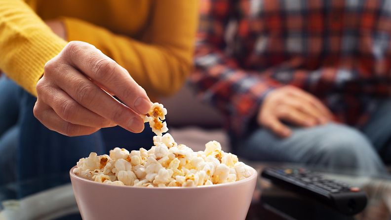 pariskunta syö popcornia ja katsoo televisiota