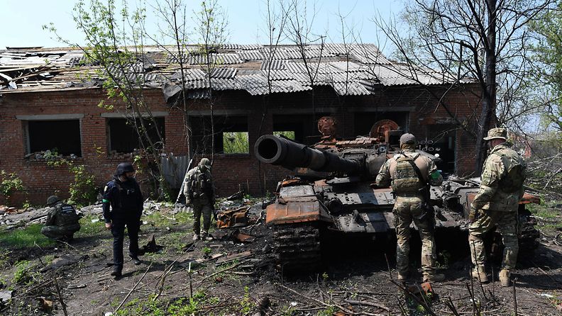 Ukrainalaisia sotilaita ja tuhoutunut tankki toukokuussa 2022.