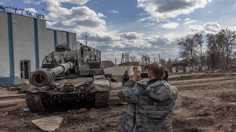 Mies kuvaa panssarihaupitsia Ukrainassa maaliskuussa 2022 EPA