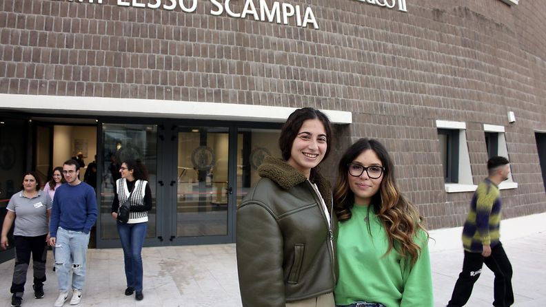 Kaksi naista poseeraa kameralle Scampian uuden yliopiston edessä.