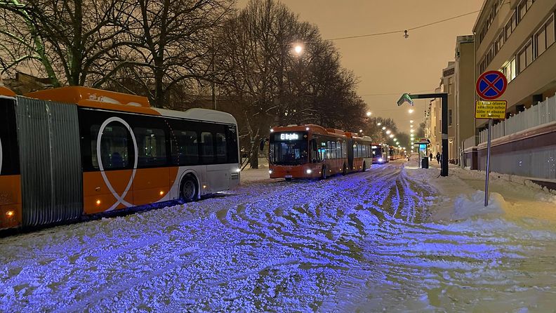 Oranssit HSL:n haitaribussit jonossa lumisessa Helsingissä.