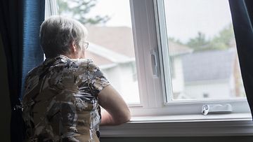 60-vuotias nainen ikkunan äärellä