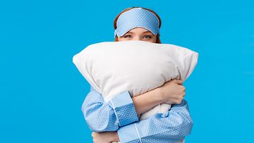 nainen pyjamassa tyyny sylissään