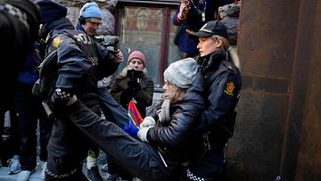 Poliisit kantavat pipopäistä Thunbergia pois mielenosoituksesta, useampi henkilö kuvaa tilannetta puhelimellaan taustalla.