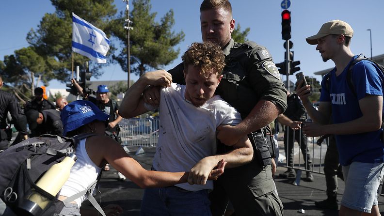 Israelin turvallisuusjoukkojen mies pitelee kiinni mielenosoittajaa.